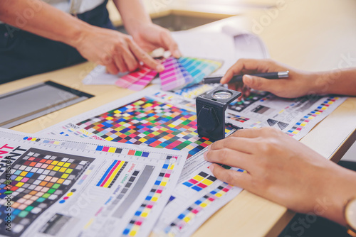 Crop image of worker checking print quality of media graphics proof print and color tone in printing industry. Selected focus