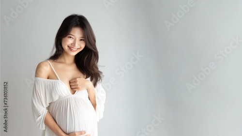 Asian pregnant woman with pregnancy belly, in soft white clothes