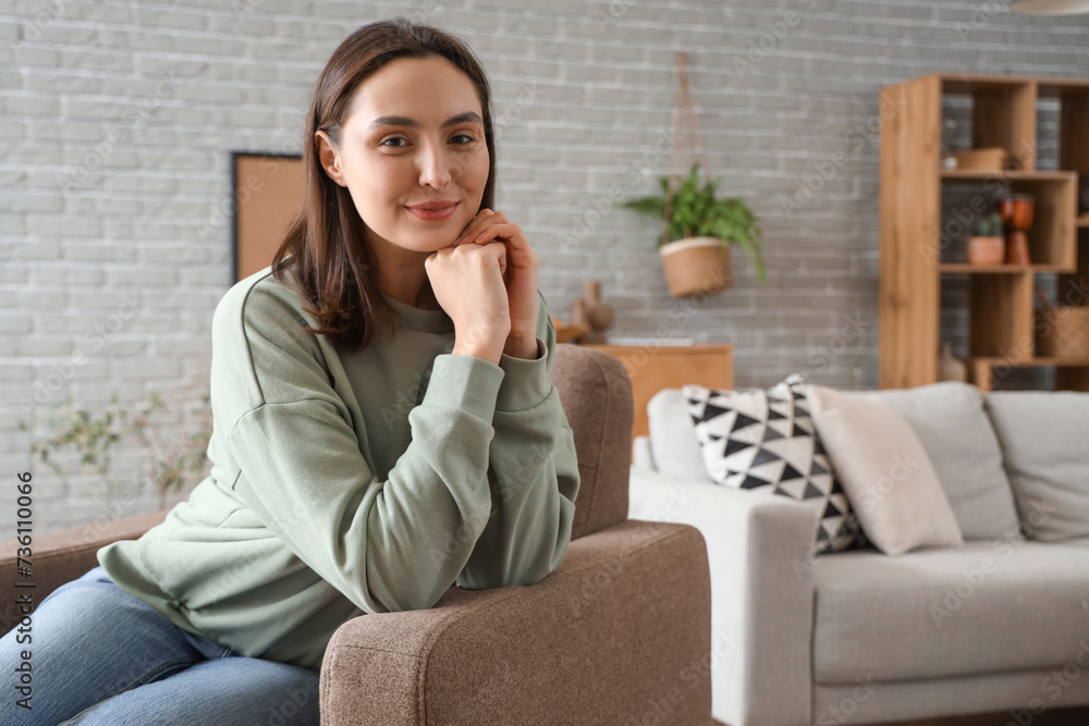 Happy young woman sitting in armchair at home Happy young woman sitting in armchair at home