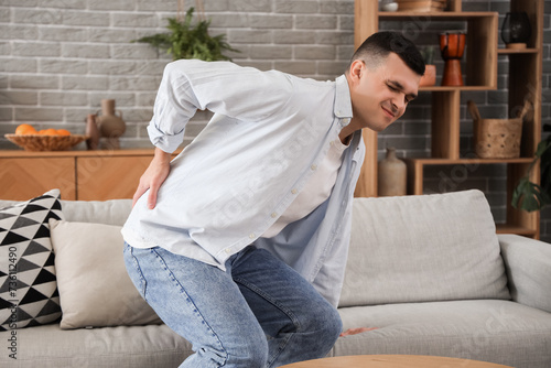 Young man suffering from back pain at home © Pixel-Shot