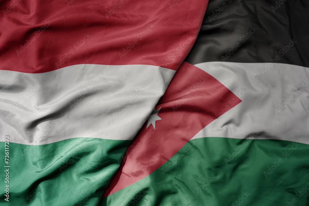 big waving national colorful flag of jordan and national flag of hungary .