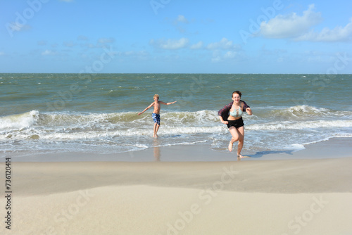 Two children have fun  on the beach, Children run out of the water