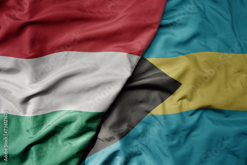 big waving national colorful flag of bahamas and national flag of hungary .