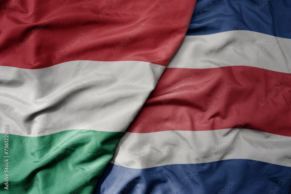 Obraz premium big waving national colorful flag of costa rica and national flag of hungary .