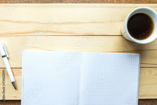 Open notebook, coffee cup and pen on wooden plank. Flat lay, top view, copy space