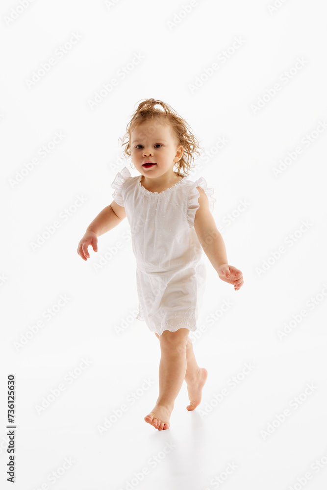 Full-length portrait of little girl with wet curly hair have fun while running against white studio background. Fun and joy. Concept of childhood, motherhood, life, carefree, birth. Copy space for ad Full-length portrait of little girl with wet curly hair have fun while running against white studio background. Fun and joy. Concept of childhood, motherhood, life, carefree, birth. Copy space for ad