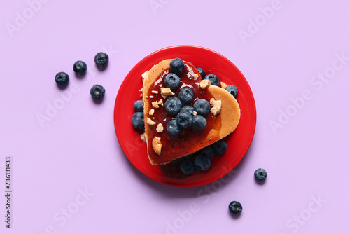 Plate with tasty pancakes in shape of heart, blueberry and jam on purple background. Valentine's Day celebration