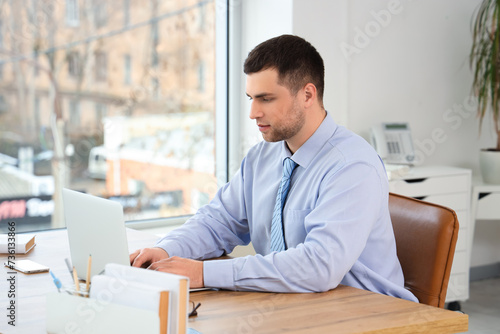 Young businessman working with laptop at table in office
