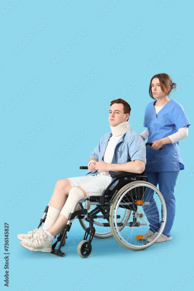 Injured young man after accident in wheelchair with doctor on blue background Injured young man after accident in wheelchair with doctor on blue background