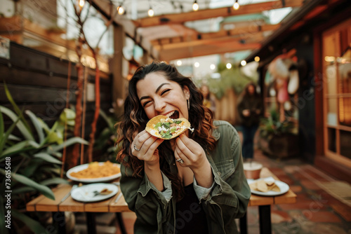 Portrait of young woman eating a delicious taco in restaurant outdoors