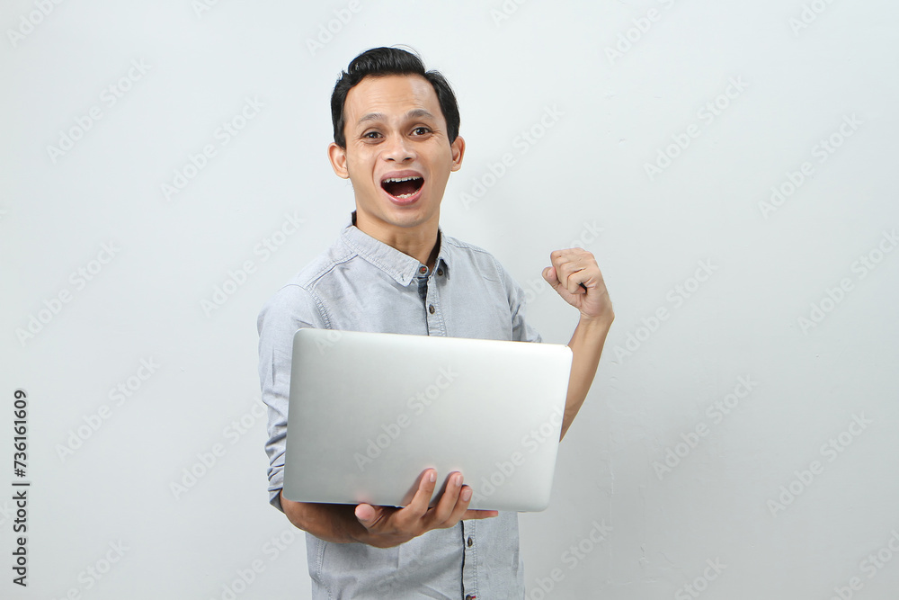 happy asian indonesian man holding laptop computer on isolated background happy asian indonesian man holding laptop computer on isolated background