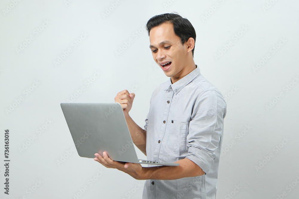 happy asian indonesian man holding laptop computer on isolated background happy asian indonesian man holding laptop computer on isolated background