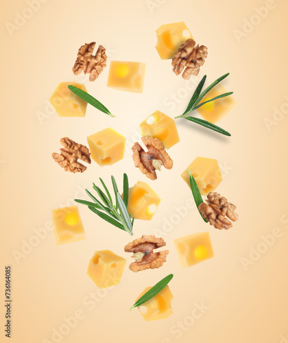 Cheese, walnuts and rosemary flying on beige background