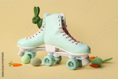 Vintage roller skates with Easter eggs, toy bunny and carrots on yellow background