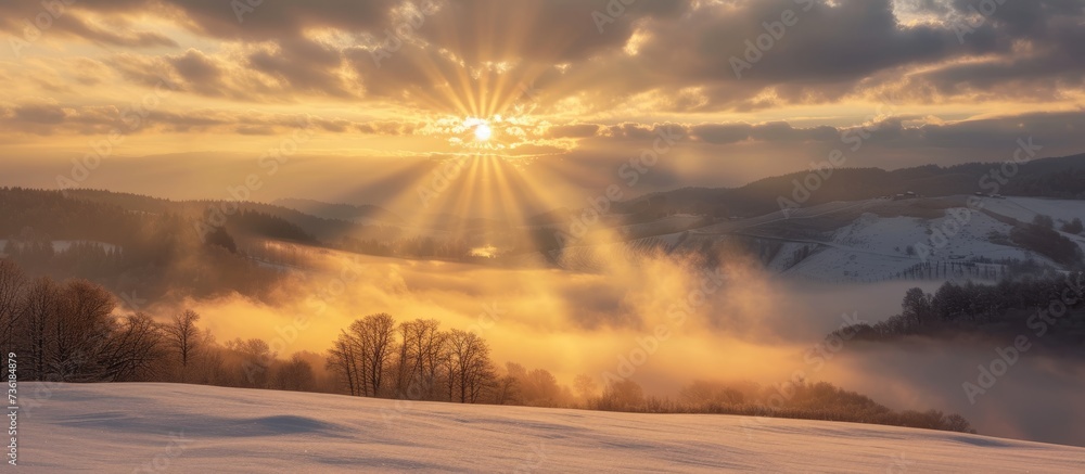 A serene snowy landscape with a radiant sun shining through the clouds on a cold winter day