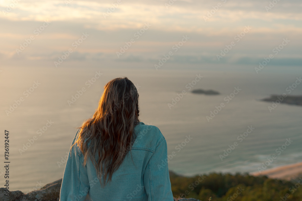 Woman sitting in Monteventoso watching the sunset in Doniños, Ferrol. Woman sitting in Monteventoso watching the sunset in Doniños, Ferrol.