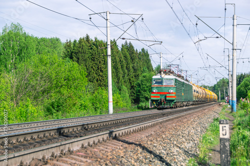 The train is moving along the railway tracks. The tank car is pulled by two locomotives. Transportation of petroleum products by rail. Tanks with flammable chemical liquids. Cars with liquefied gas.