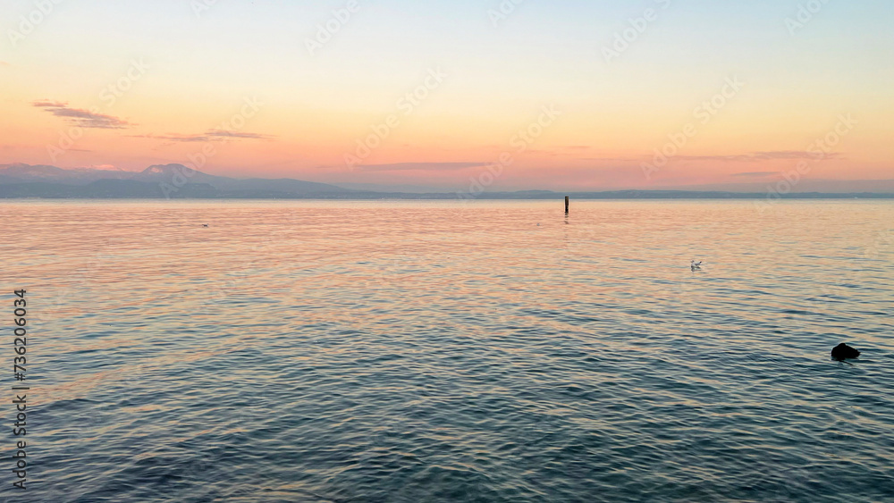 Sunset view of the beautiful Lake Garda. Sirimione, Italy. Mobile photo, copy space.