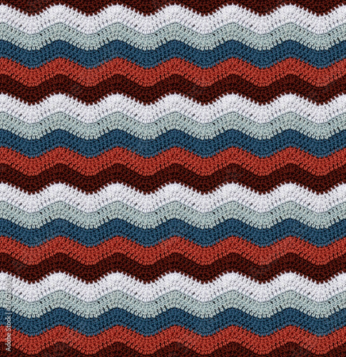 Seamless knitted pattern in the form of zigzags crocheted with threads of contrasting colors. Cotton yarn. African style.