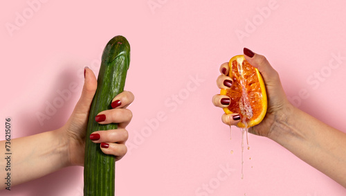 Obraz na plátně Female hand with half of juicy orange and cucumber on pink background
