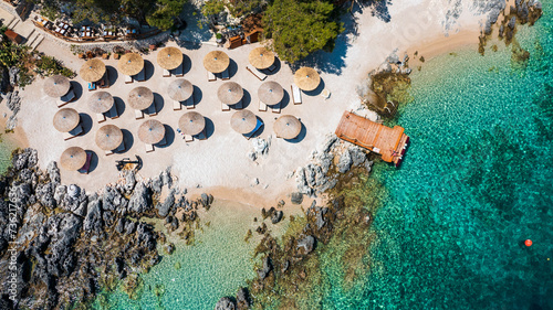 Obraz na płótnie
A top-down view of the rocky coastline of a luxury resort with reed umbrellas and deckchairs for sunbathing. w salonie