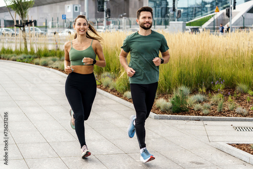 Fototapeta Naklejka Na Ścianę i Meble -  Active couple jogging together in urban park setting, promoting fitness.