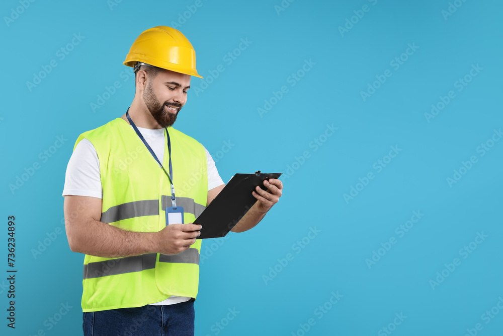 Engineer in hard hat holding clipboard on light blue background, space for text Engineer in hard hat holding clipboard on light blue background, space for text
