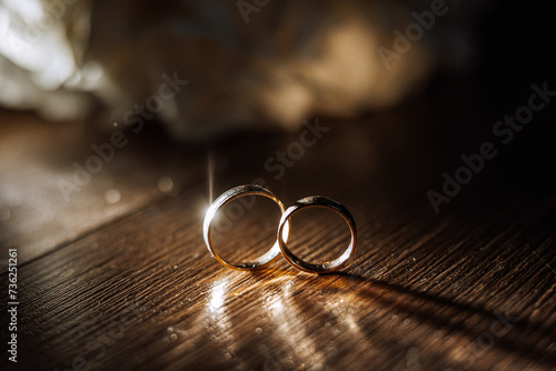 Stylish wedding rings on a wooden table. Promises engagement. Luxury marriage and wedding accessory concept. two wedding rings and a wedding invitation. photo