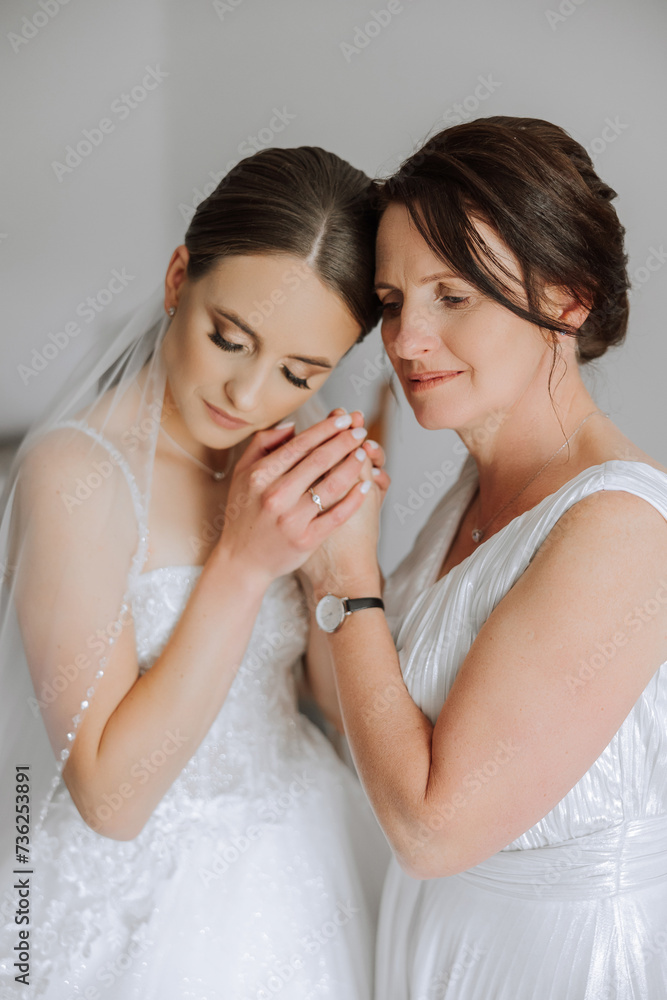 A beautiful and happy mother and her daughter, the bride, are standing next to each other. The best day for parents. Tender moments at the wedding. A beautiful and happy mother and her daughter, the bride, are standing next to each other. The best day for parents. Tender moments at the wedding.