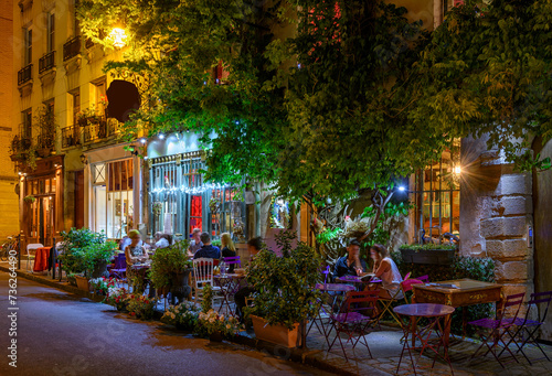 Fototapeta Naklejka Na Ścianę i Meble -  Cozy street with tables of cafe in Paris, France. Night cityscape of Paris. Architecture and landmarks of Paris.