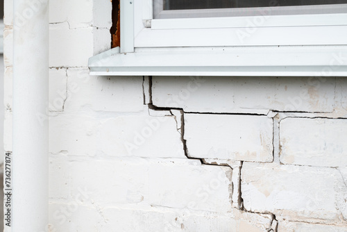 Cracked brick wall of private house. Crack under the window on white brick wall, problems with foundation