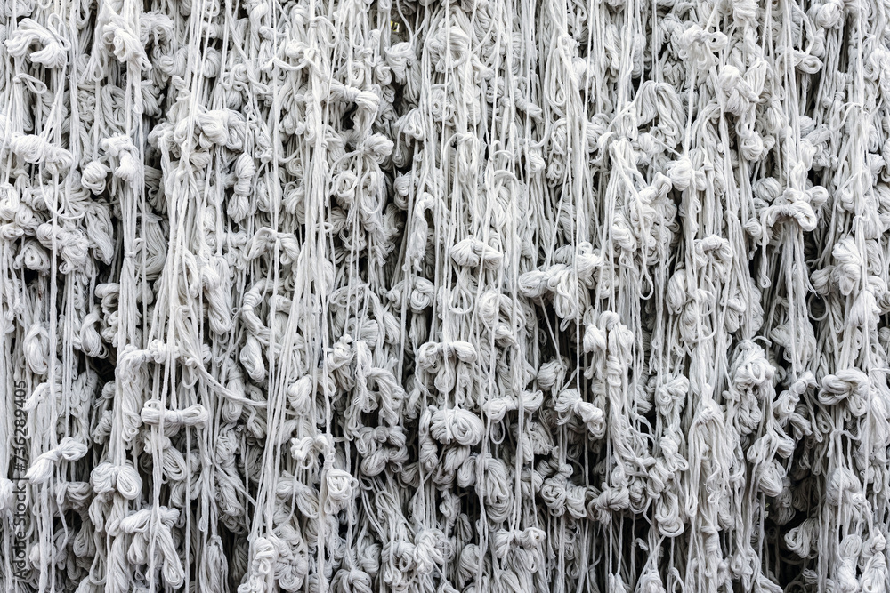 Obraz premium Pattern of holy thread background. Many white tassels made of many tied holy threads for pray and merit of Thai culture and religion. Skein of white yarn on neutral background. Cotton line texture.