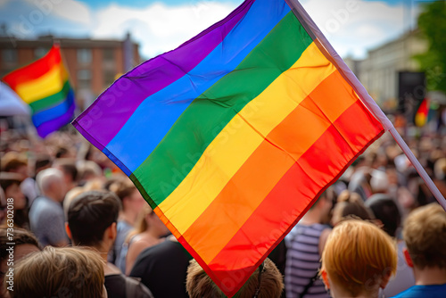 Photo of a man hodling LGBT Flag during pride march with crowd photo