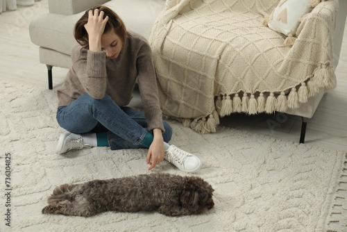 Sad young woman and her dog sitting on floor at home photo