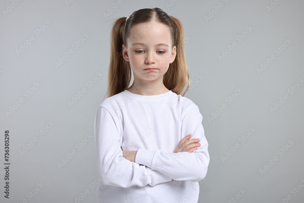 Portrait of sad girl with crossed arms on light grey background Portrait of sad girl with crossed arms on light grey background