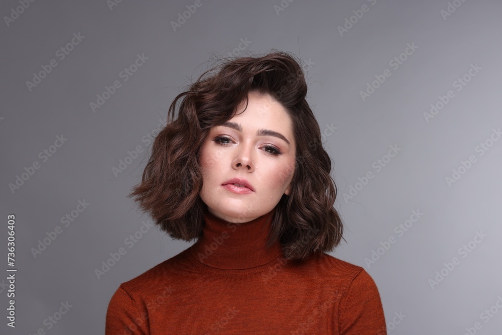 Portrait of beautiful young woman with wavy hairstyle on grey background Portrait of beautiful young woman with wavy hairstyle on grey background