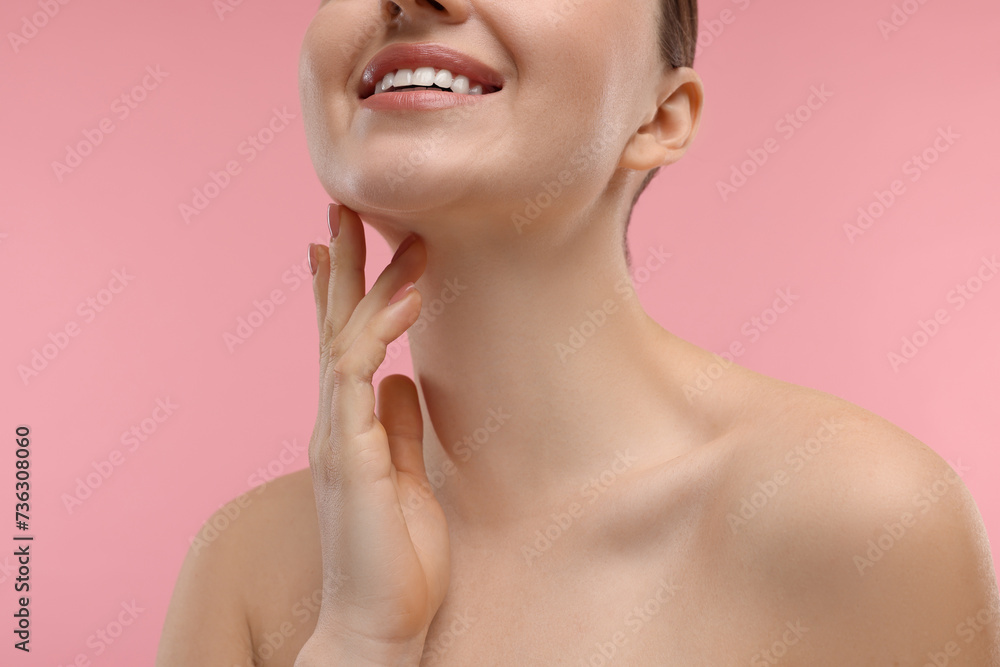 Smiling woman touching her neck on pink background, closeup Smiling woman touching her neck on pink background, closeup