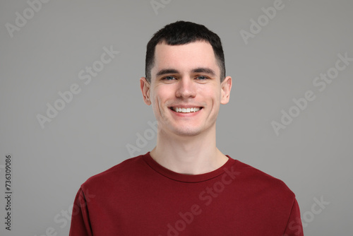 Handsome young man with clean teeth smiling on grey background © New Africa