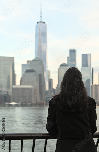 woman looking at downtown manhattan nyc skyline (after sunset, night time)  world trade center cityscape (high rise urban buildings) railing, hudson river, waterfront, bay, harbor new york city view photo