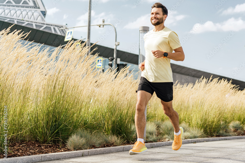 Jogger with a fitness tracker enjoying a run in a sunny park with tall grasses.