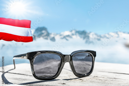 Sonnenbrille auf einem Holztisch  mit Schneebergen in Österreich