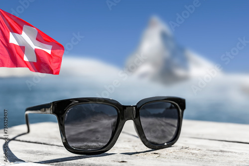 Sonnenbrille auf einem Holzdeck mit Matterhorn und Schweizer Flagge