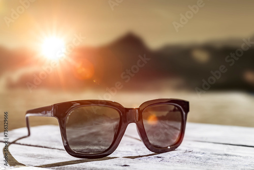 Sonnenbrille auf einem Holztisch  in den Bergen bei sonnenutergang