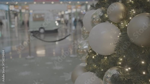 Christmas tree decorated with baubles and illuminated lights with blurred background in shopping mall. New Year decoration in shopping center. People walking in background. photo