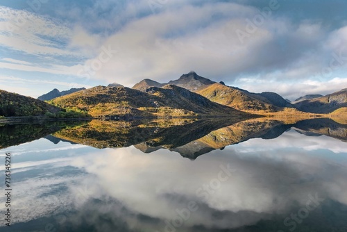 beautiful mountainous landscape in Norway reflected on the water with clouds ...