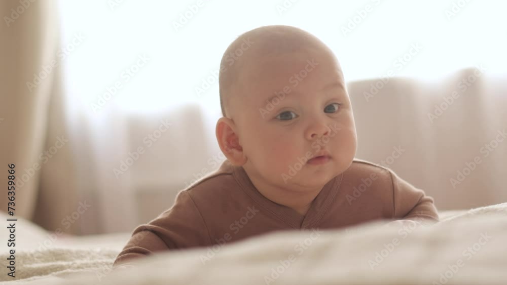 The baby lies on his stomach and looks thoughtfully slow motion close-up The baby lies on his stomach and looks thoughtfully slow motion close-up