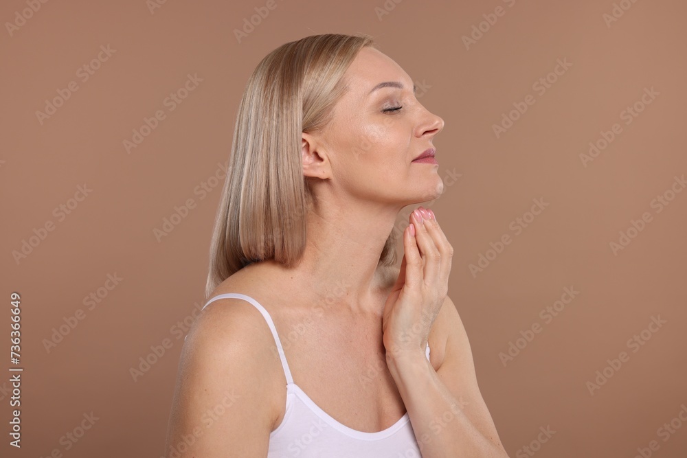Beautiful woman touching her neck on beige background Beautiful woman touching her neck on beige background