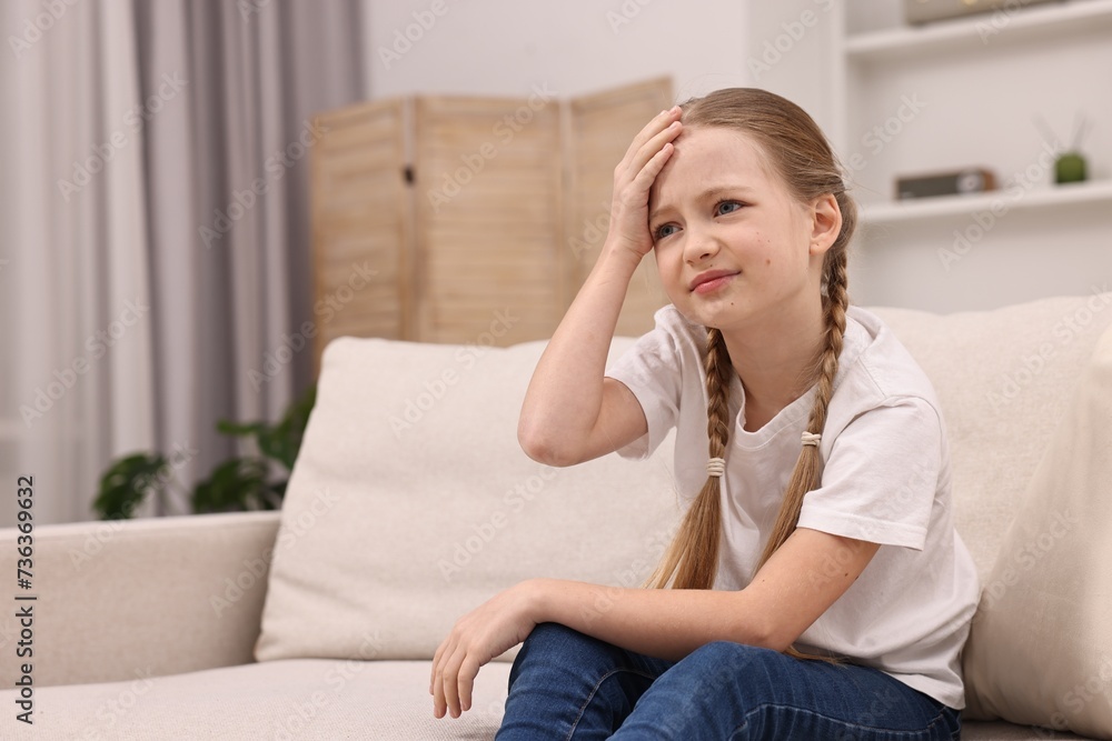 Little girl suffering from headache on sofa indoors Little girl suffering from headache on sofa indoors