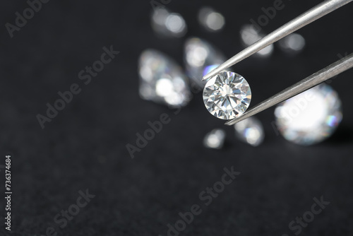 Tweezers with beautiful shiny diamond against dark blurred background, closeup. Space for text © New Africa