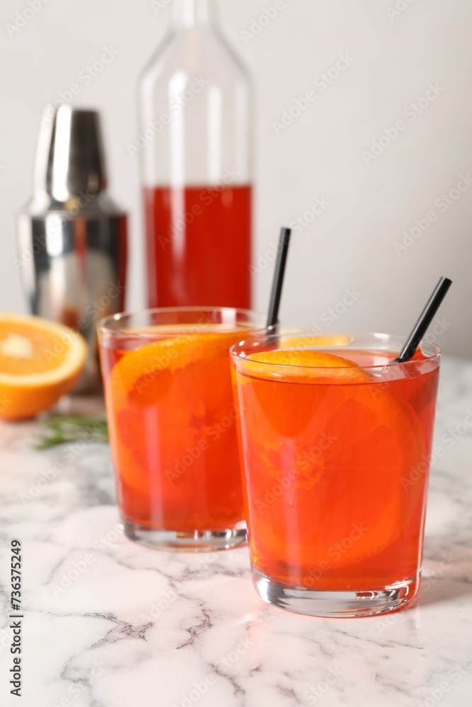 Aperol spritz cocktail, orange slices and straws in glasses on white marble table Aperol spritz cocktail, orange slices and straws in glasses on white marble table